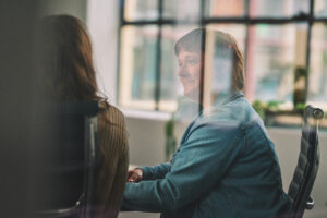 a female marketer is seen working in an office meeting room through the glass
